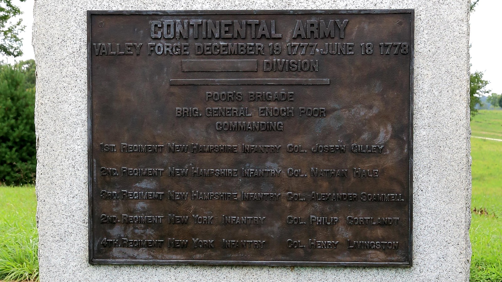 A large, smoothed, granite block with bronze plaque, sides and bottom rough.