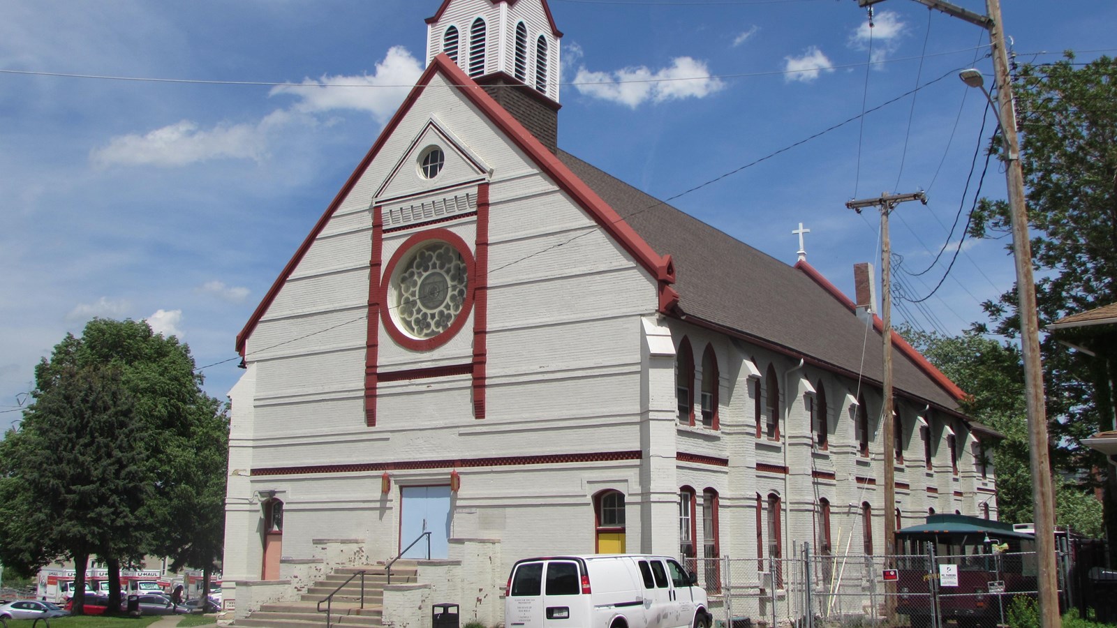 Two-story Gothic Revival church with front gable, and centered steeple and entrance.