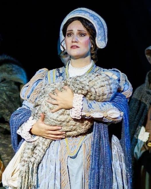 A young woman in 1580s dress holding a baby