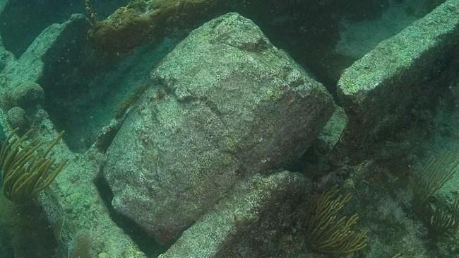 Barrell shaped concrete object resting in the bones of an underwater shipwreck