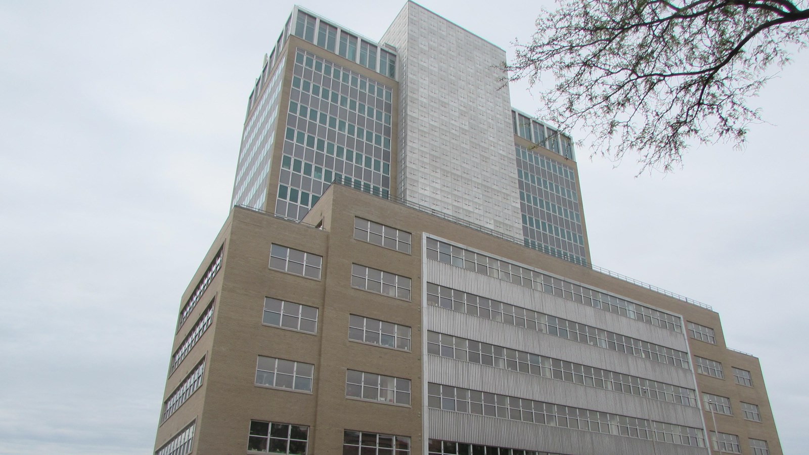 Six story building with fifteen story addition. Addition has central block with windowed wings.