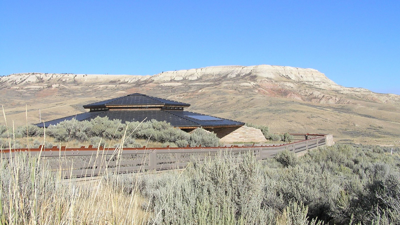 The visitor center with a butte in the background and grasses in the foreground.