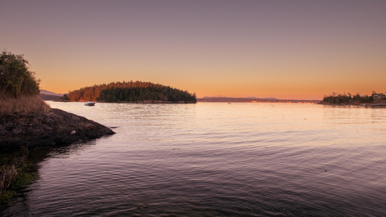 Colorful photograph of a sunset over the water with an island in the distance