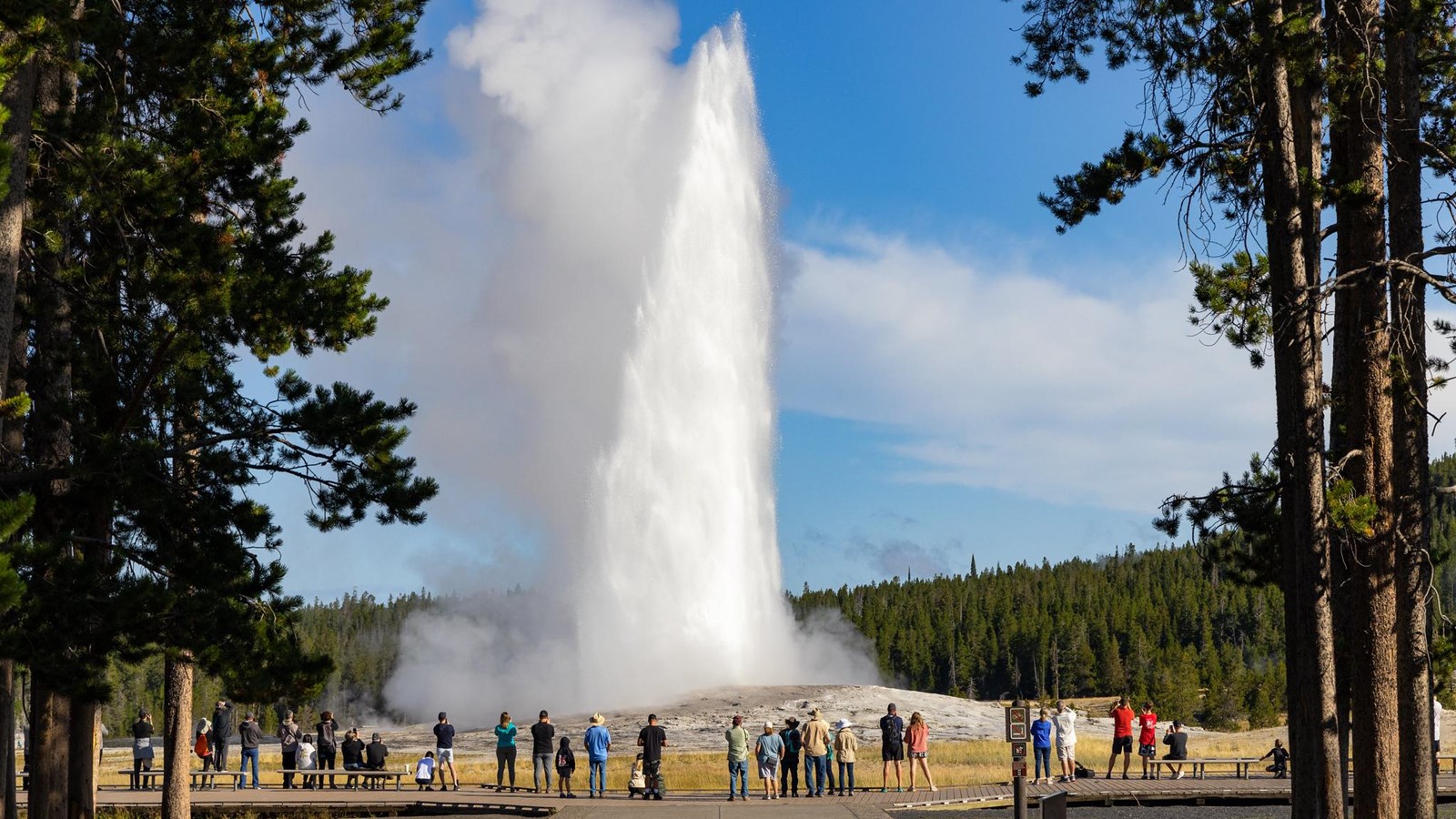 Steam rises off a river in front of a large, log cabin style building.