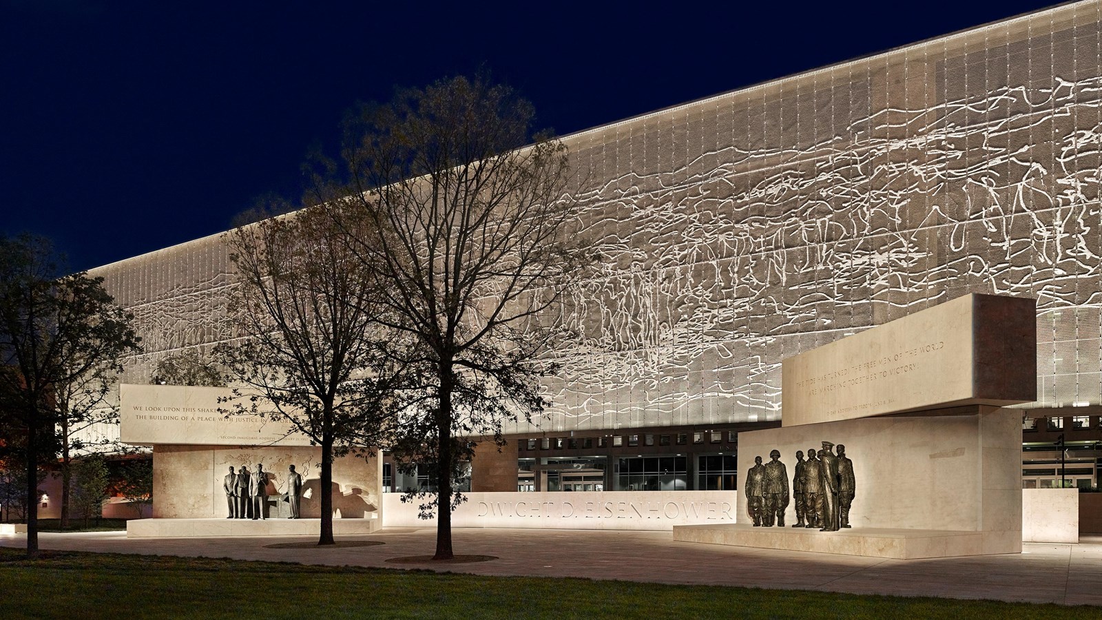 2 groups of bronze statues with a large metal mesh screen in the background.
