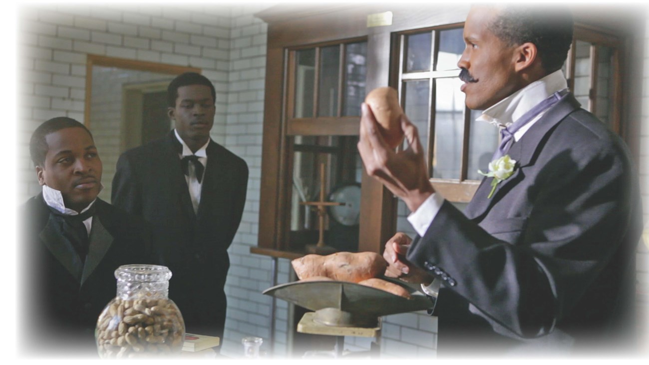 Three men dressed in period clothing. One man is holding a sweet potato. 