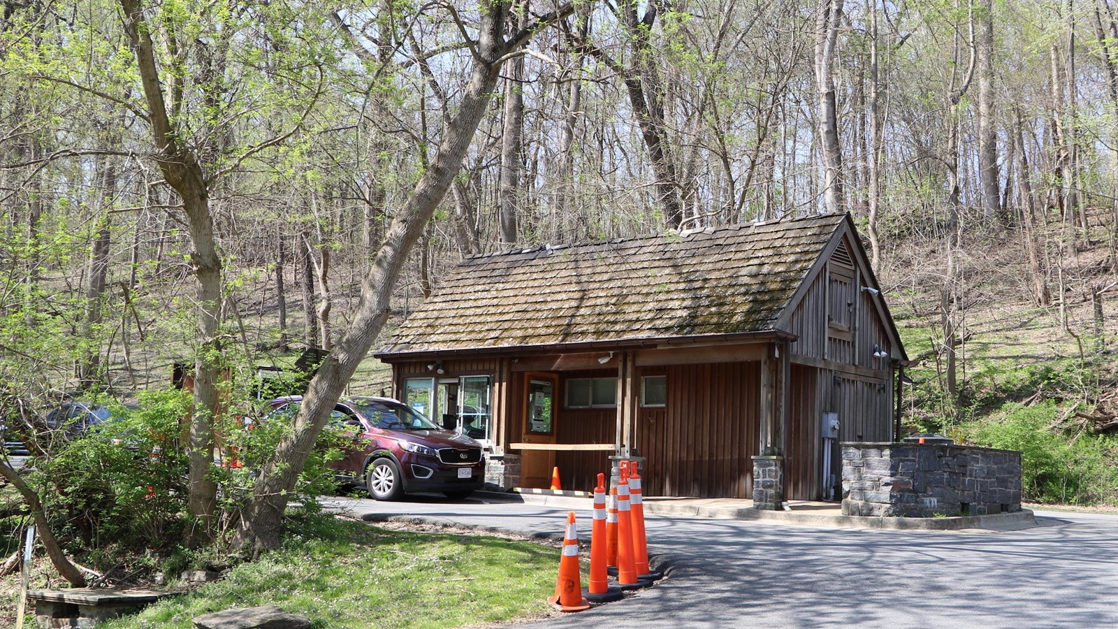 A small wooden structure in woods next to a road.