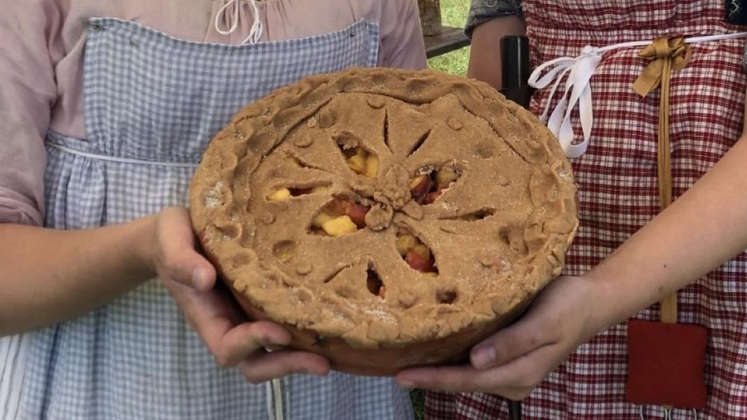 Living historians holding a pie.