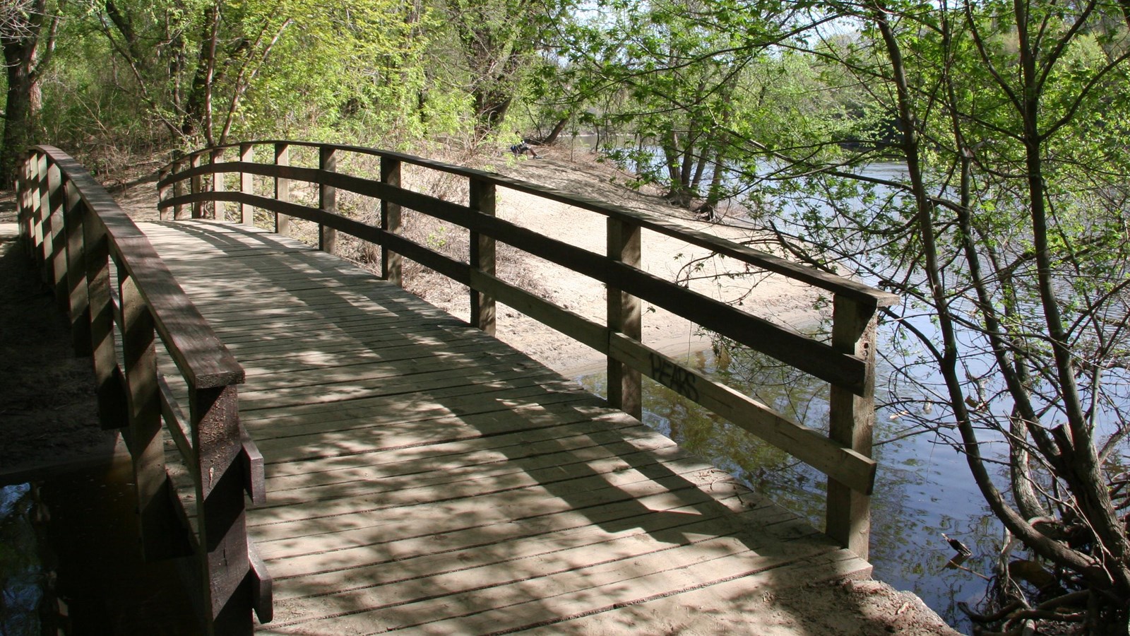 A bridge crossing a creek next to the river.  