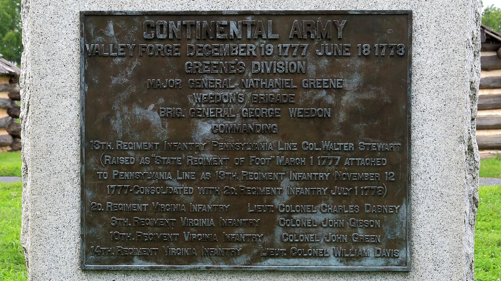 A large, smoothed granite block with a bronze plaque and rough sides and bottom.