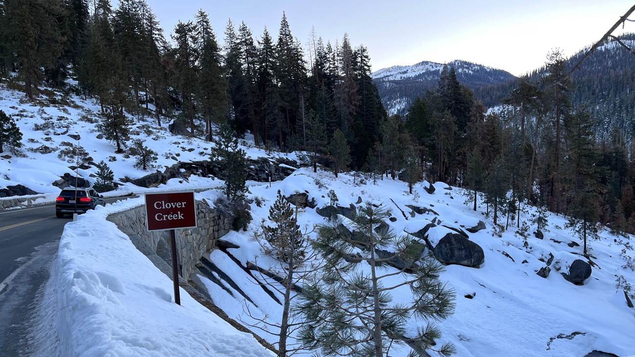 A snowy landscape of a road going over a creek.