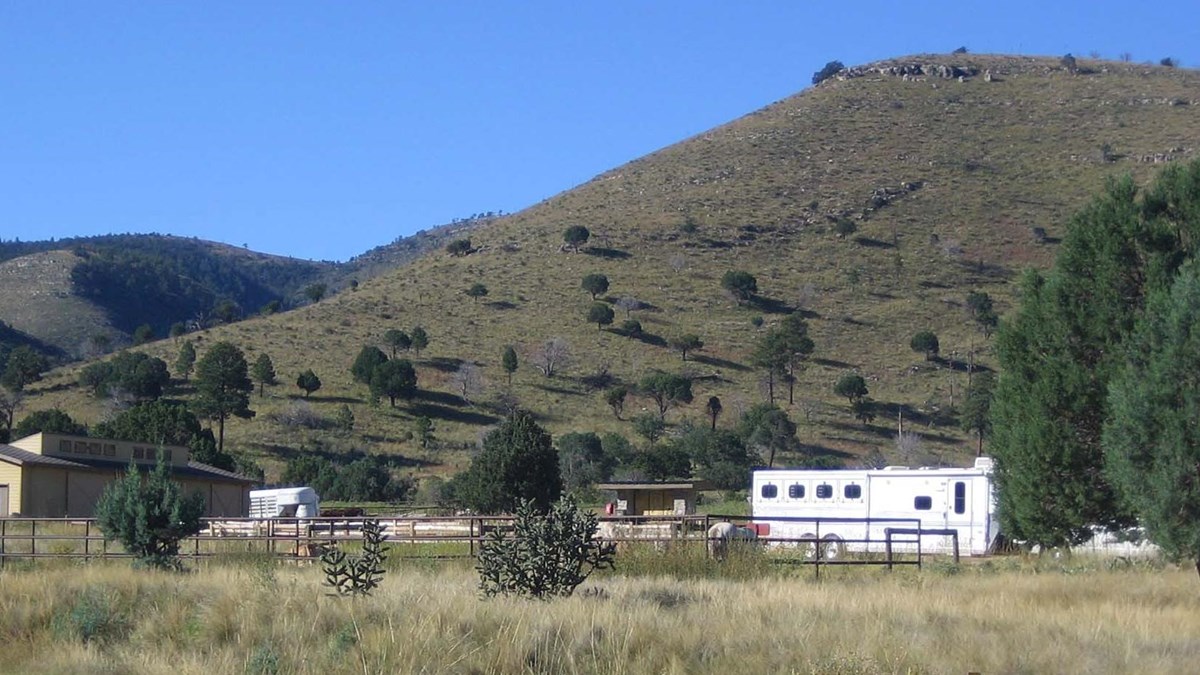 Horse corrals and camping trailers with desert hills rising behind.