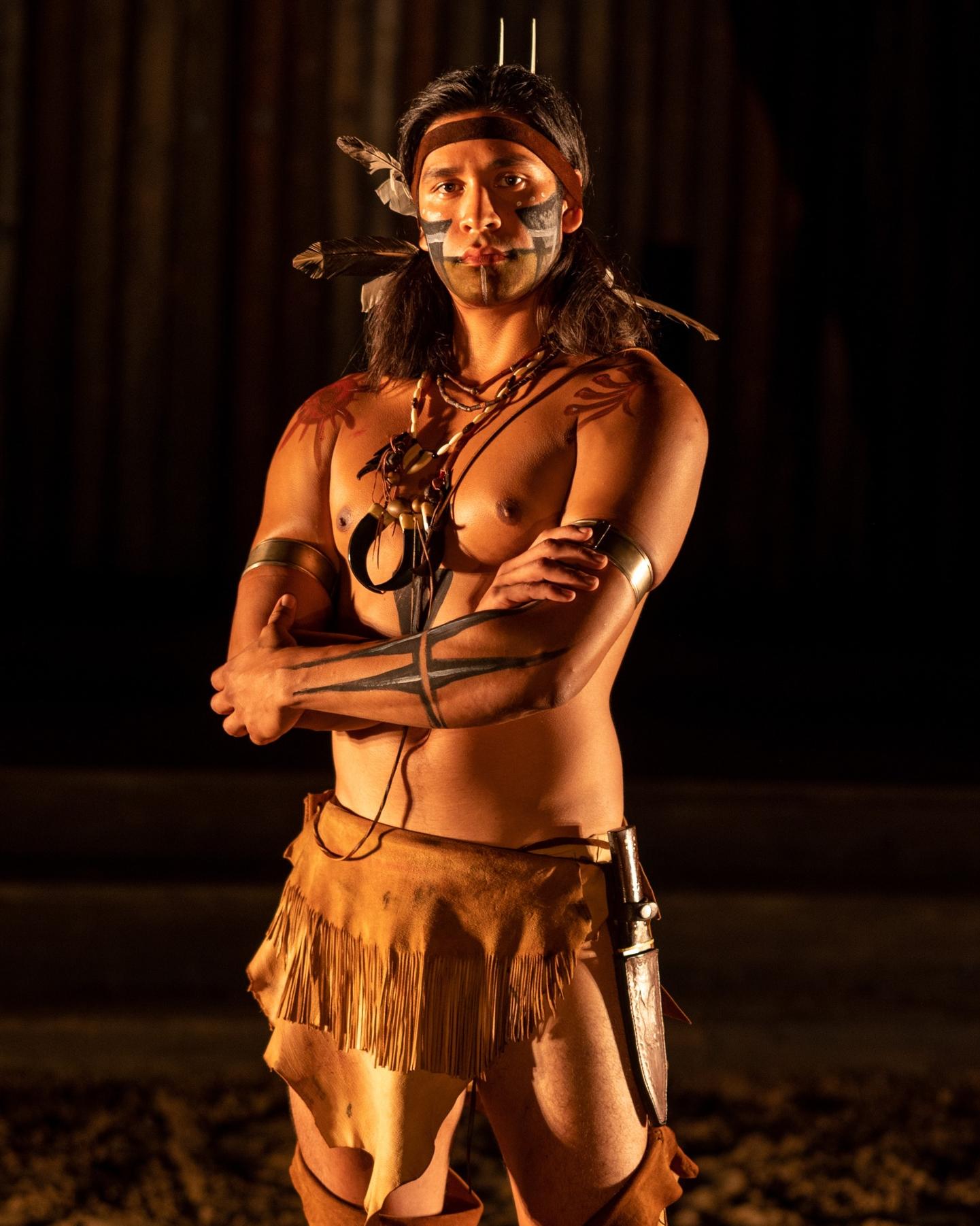 A young man wearing animal skins and decorative paint