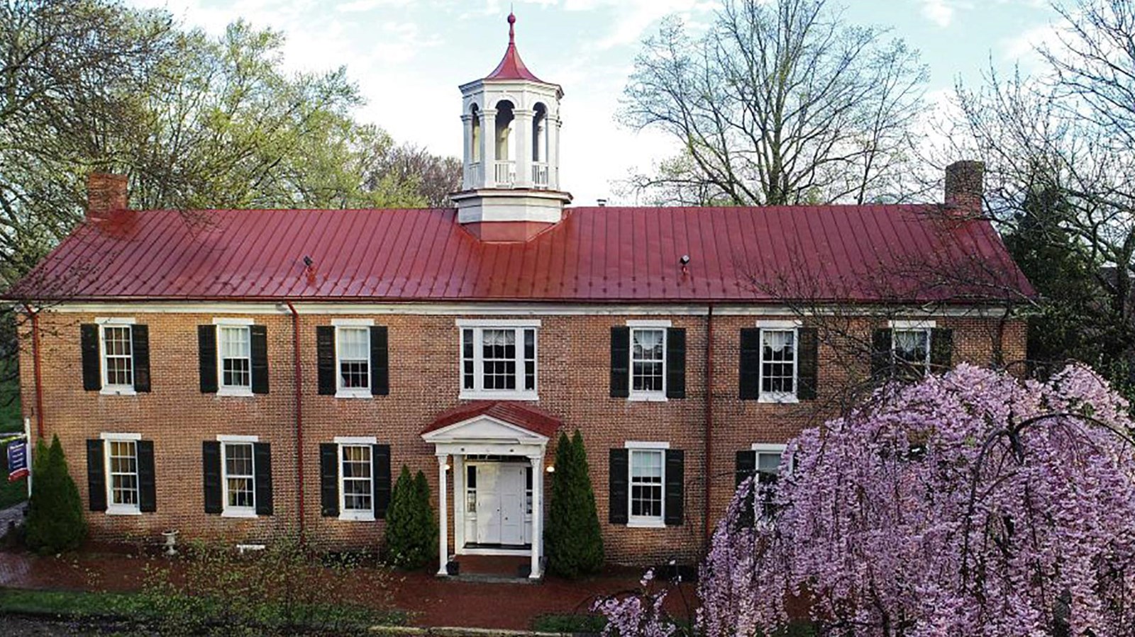 A red stoned building with a red shingle roof. 