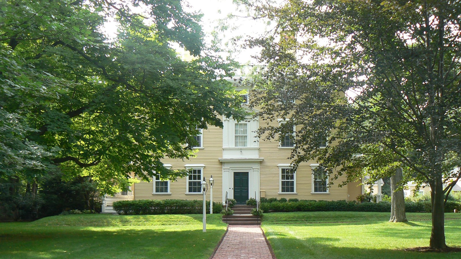 Large symmetrical Georgian house partially obscured by large trees