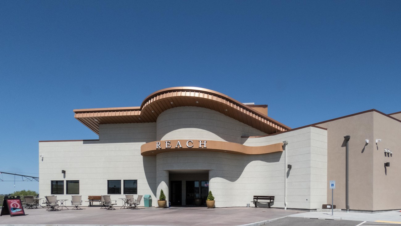 Color photograph of a cement brick building with an ornate copper roof. A sign reads 