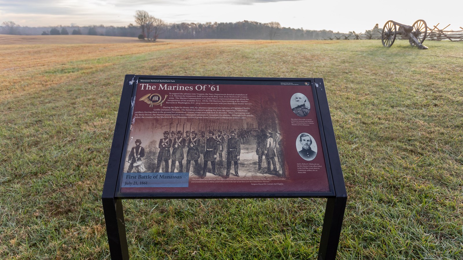 A informational panel in front of a grassy field. 
