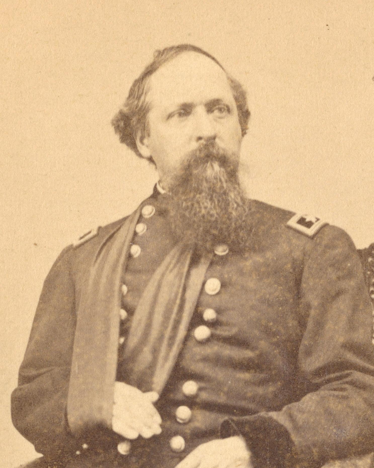A US Civil War general poses for a seated portrait in uniform and with his arm in a sling. 