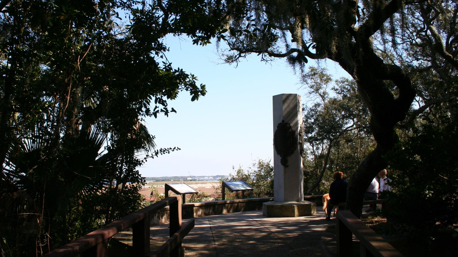 a stone monument overlooks a river surrounded by trees