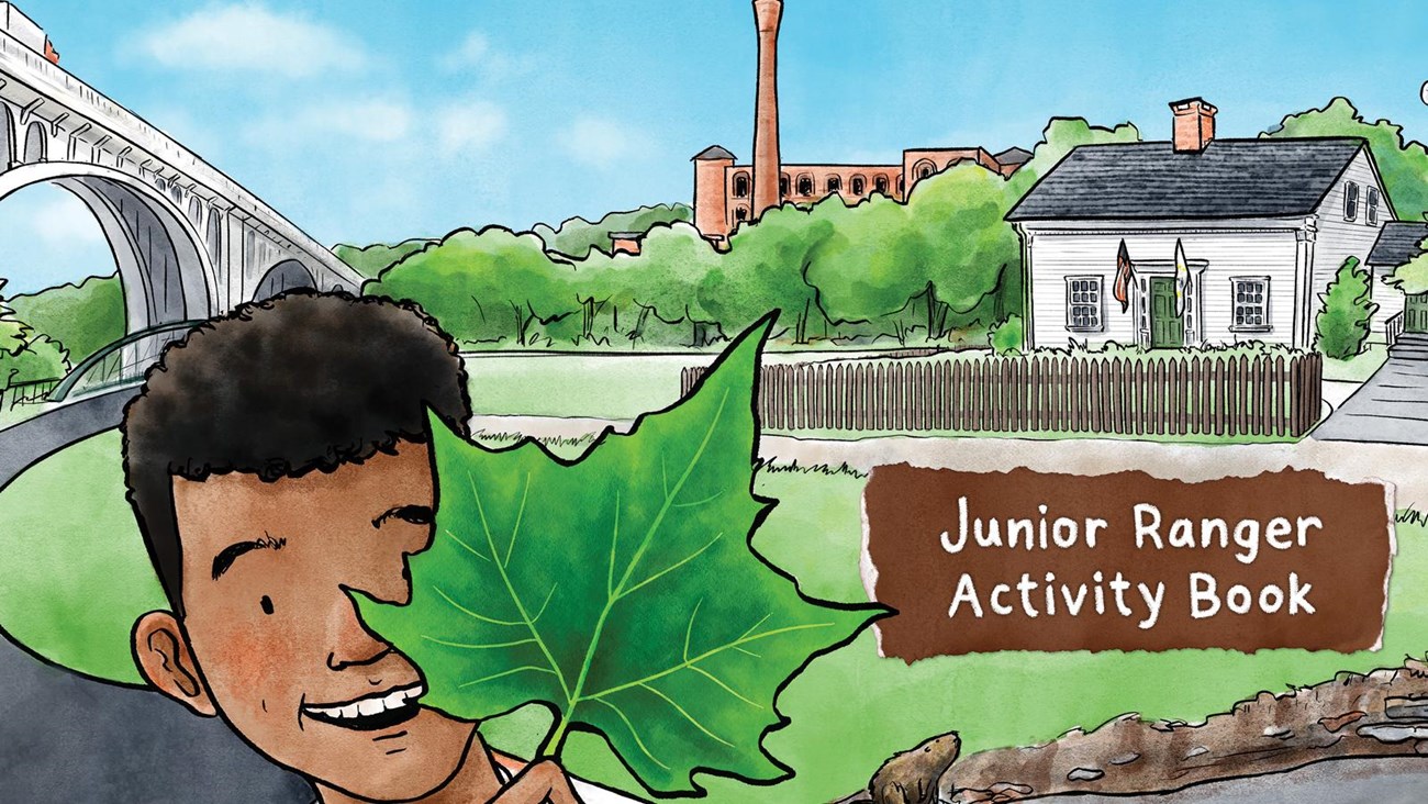 Child with large leaf stands in front of a white building, mill, and bridge