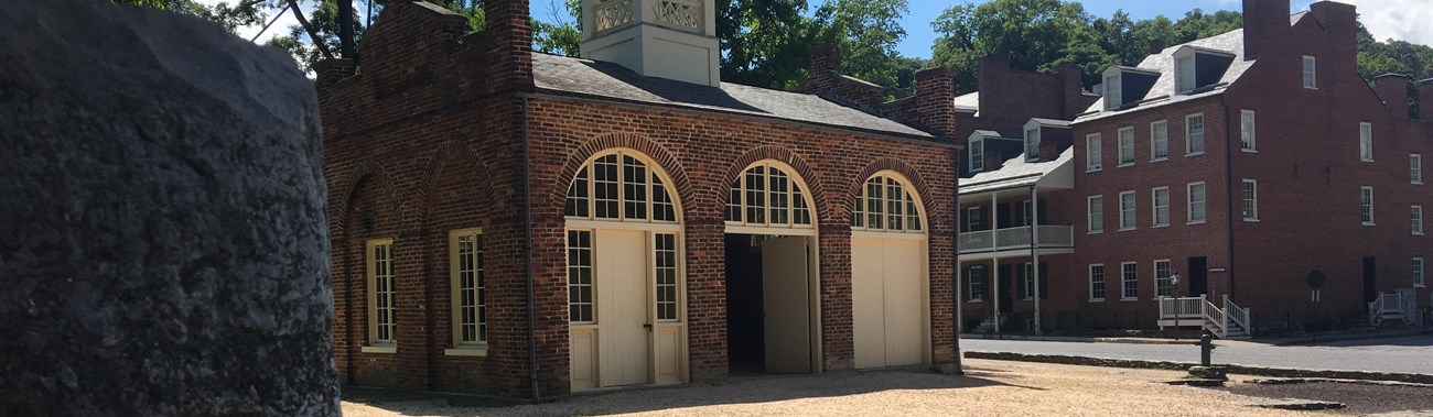 small brick building that is John Brown\'s Fort with other Lower Town buildings in the background