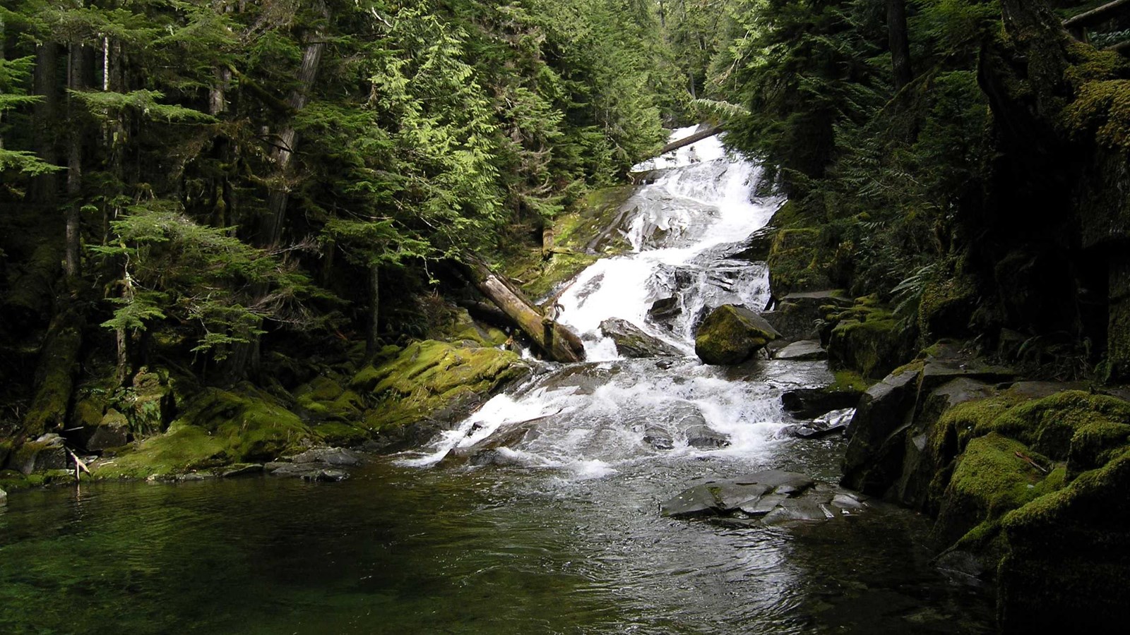 Waterfall cascading over smooth bedrock into pool