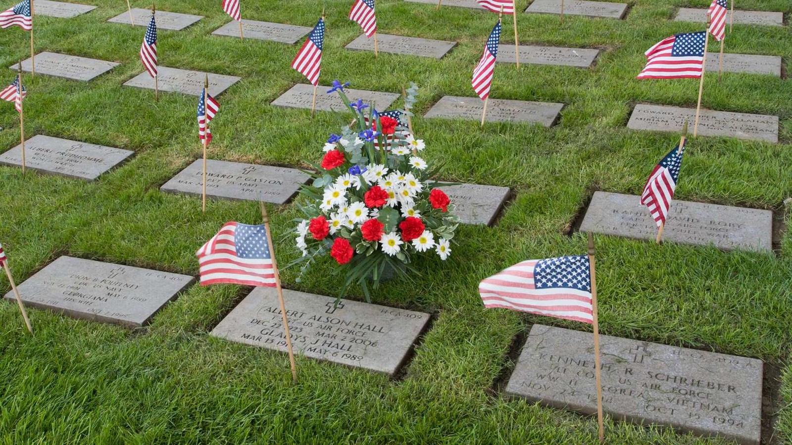 Rows of cremation grave markers lay flat against the grass with miniature US flags marking each one.