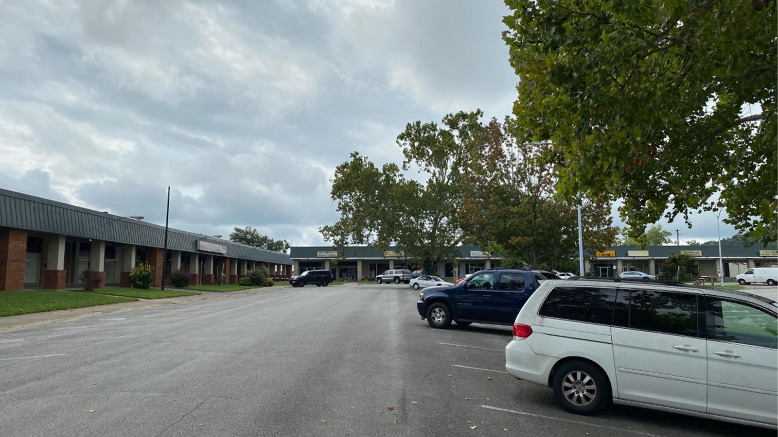 A strip mall with several cars parked in the lot