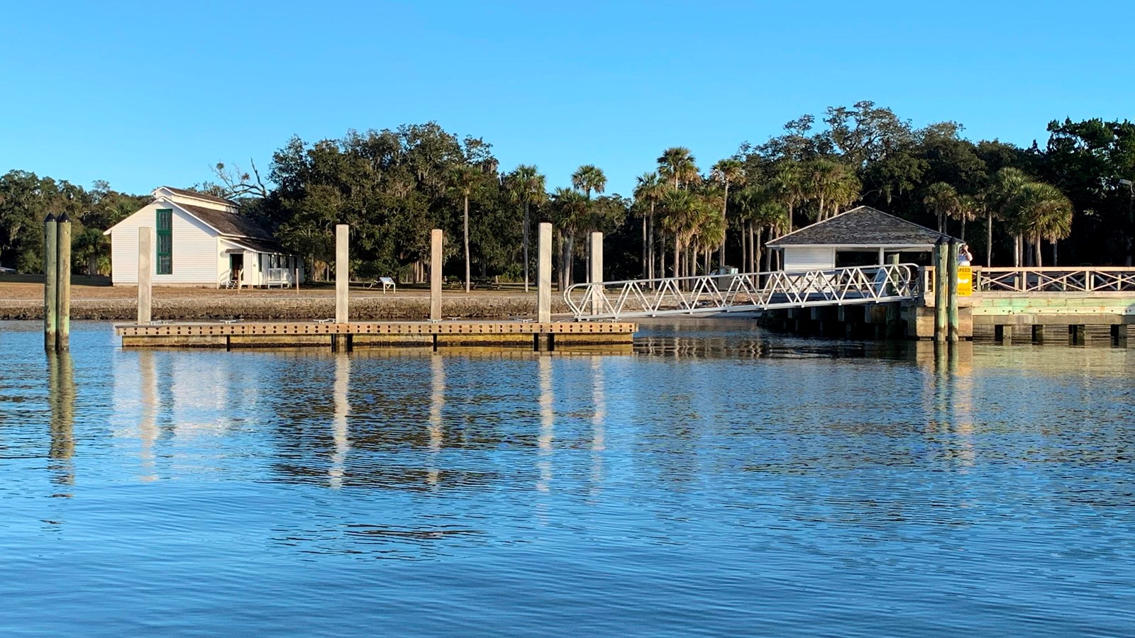 A floating dock in the river with a white building in the background