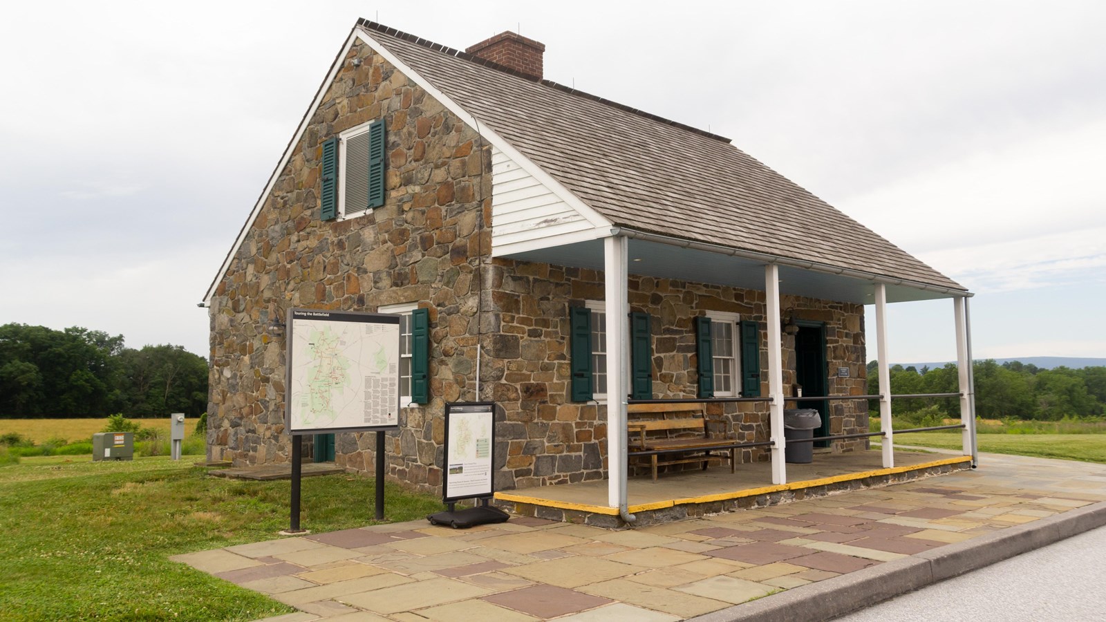 One and a half story stone building with a-frame roof, overhanging porch, and informational map.