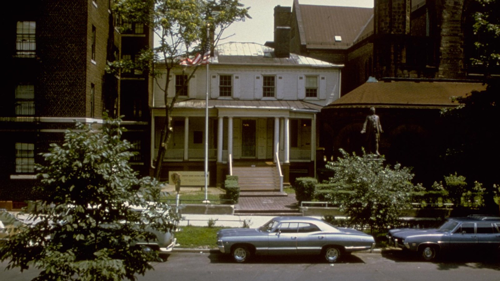 A white house, Hamilton Grange, sits between two larger buildings on either side.