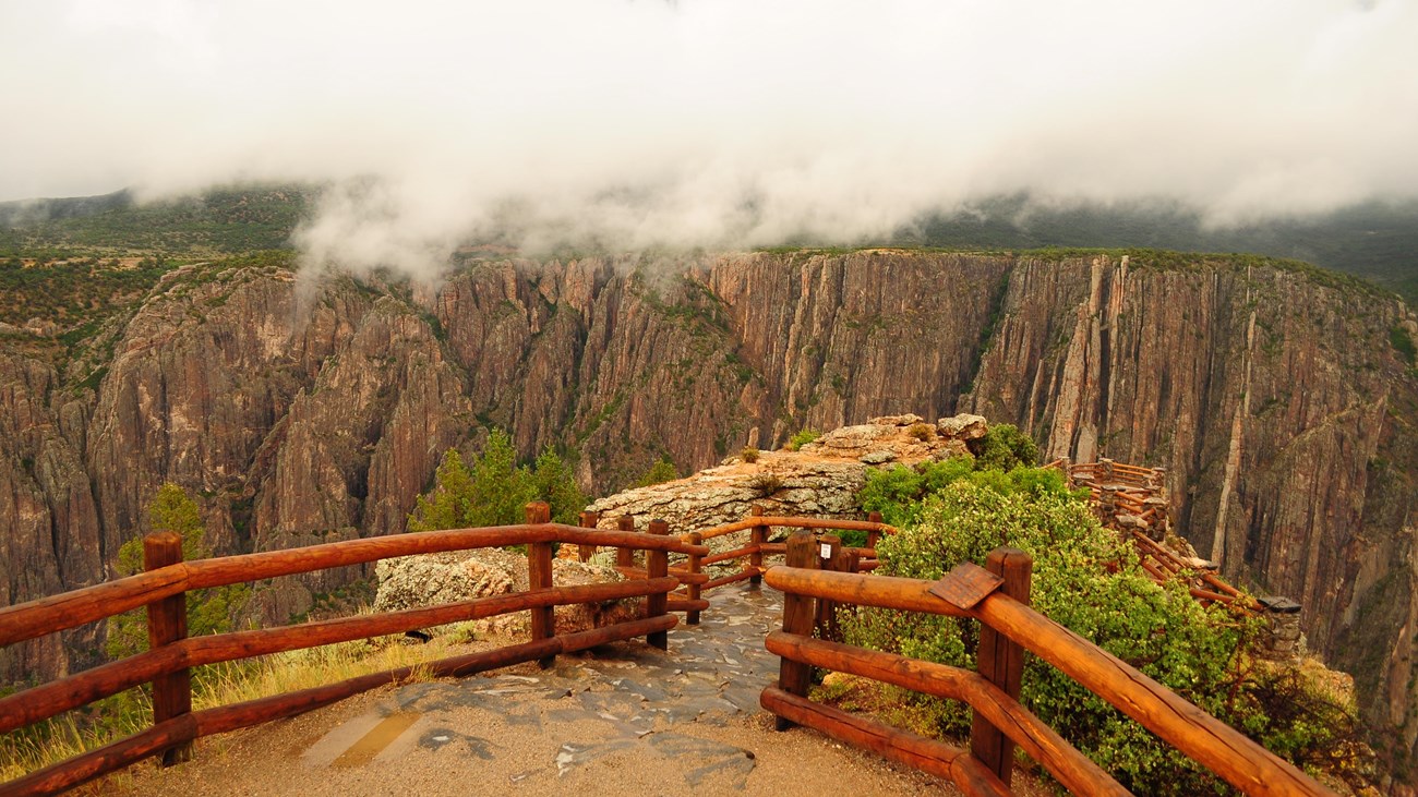 An overlook lined with wooden fencing leading towards a canyon edge