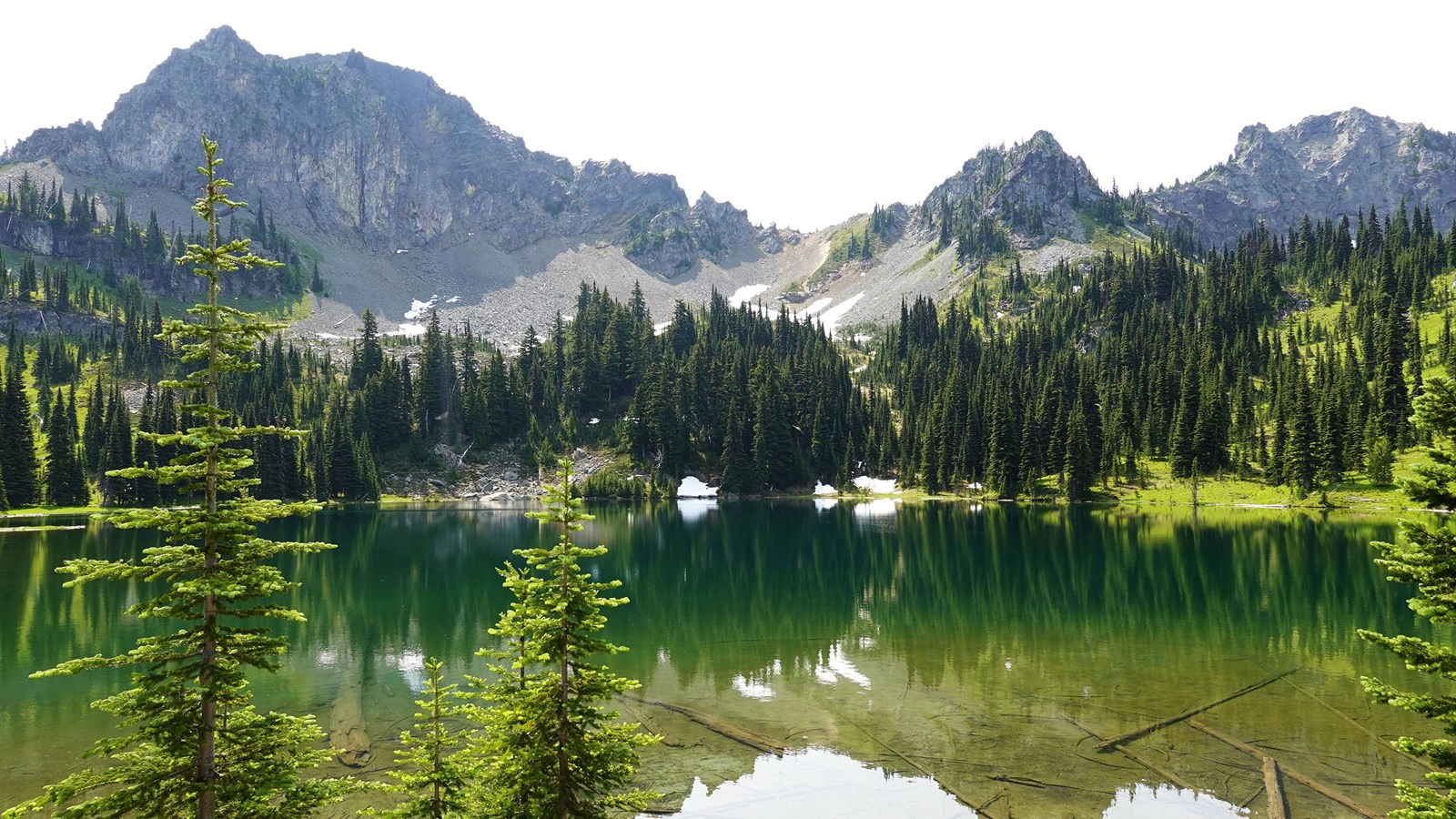 Rocky peaks reflect in the still waters of a small mountain lake. 