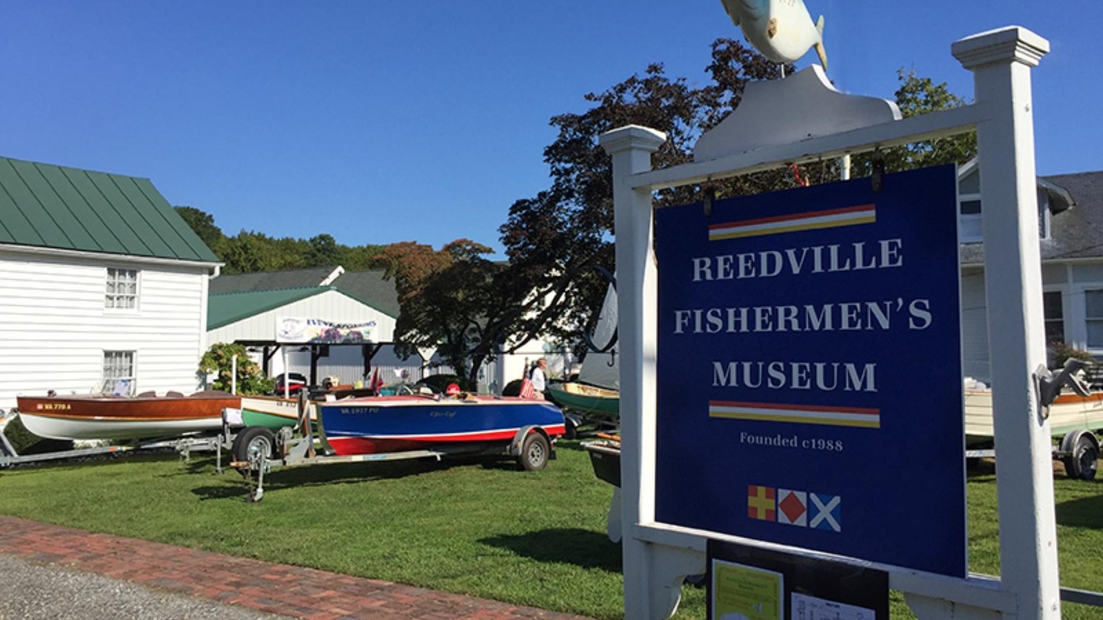 Entrance to the Reedville Fishermen\'s Museum with a large blue sign and small boats on display.