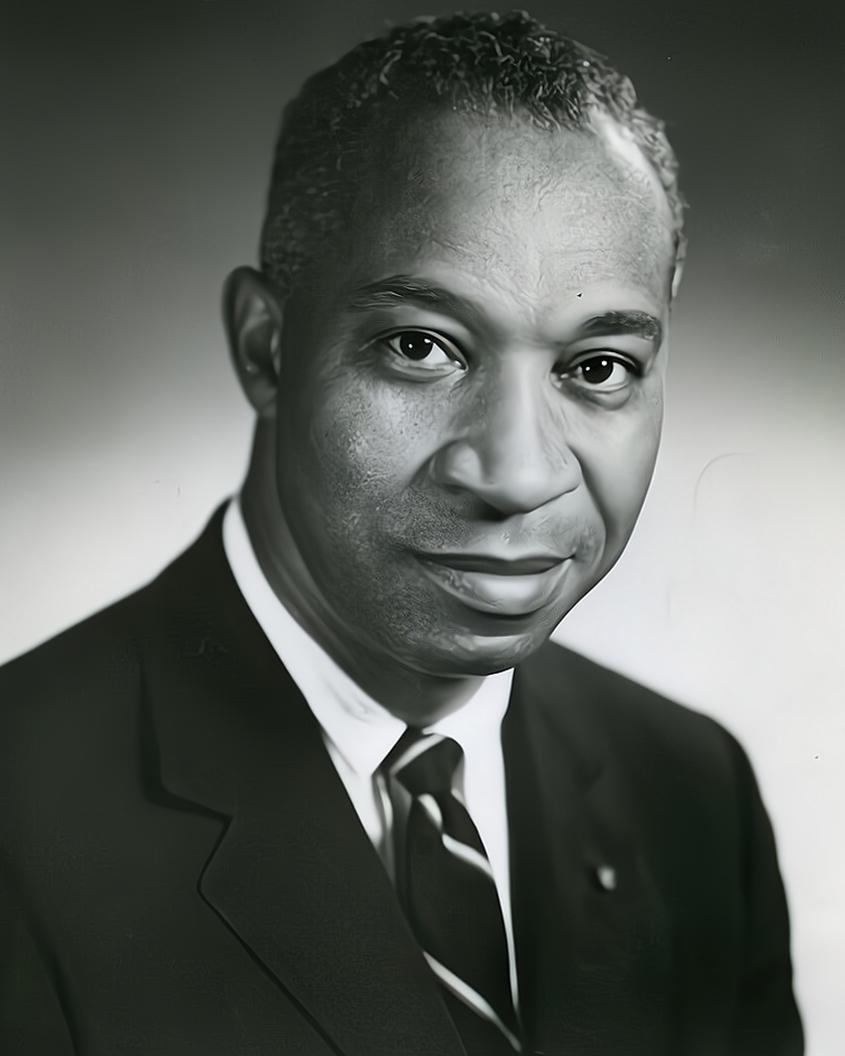 A black and white image of a man wearing a sport coat and tie