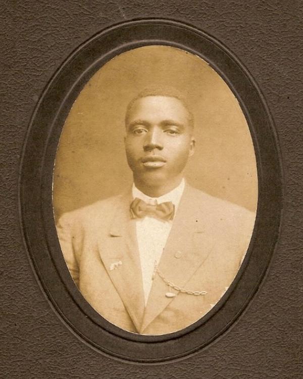 Portrait of young black man in a suit and bow tie.