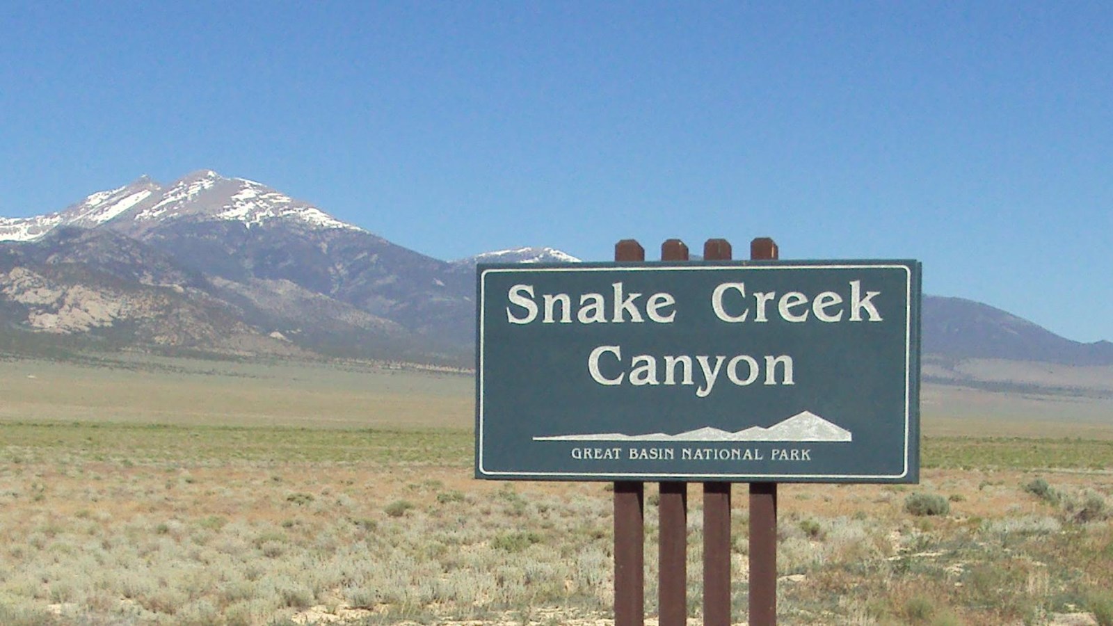 Green and white road sign for Snake Creek road