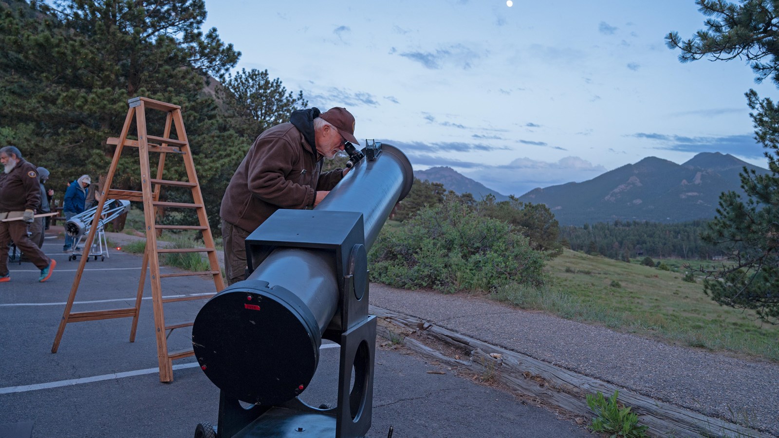 An NPS night sky volunteer is looking at the stars with a telescope