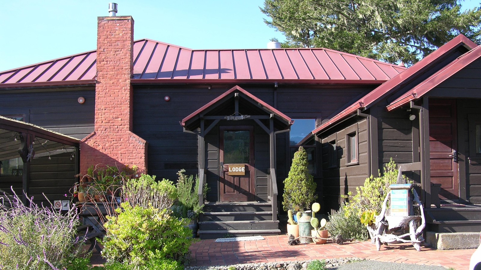A photo of the main entrance to a one-story, brown-sided, red-roofed building. 