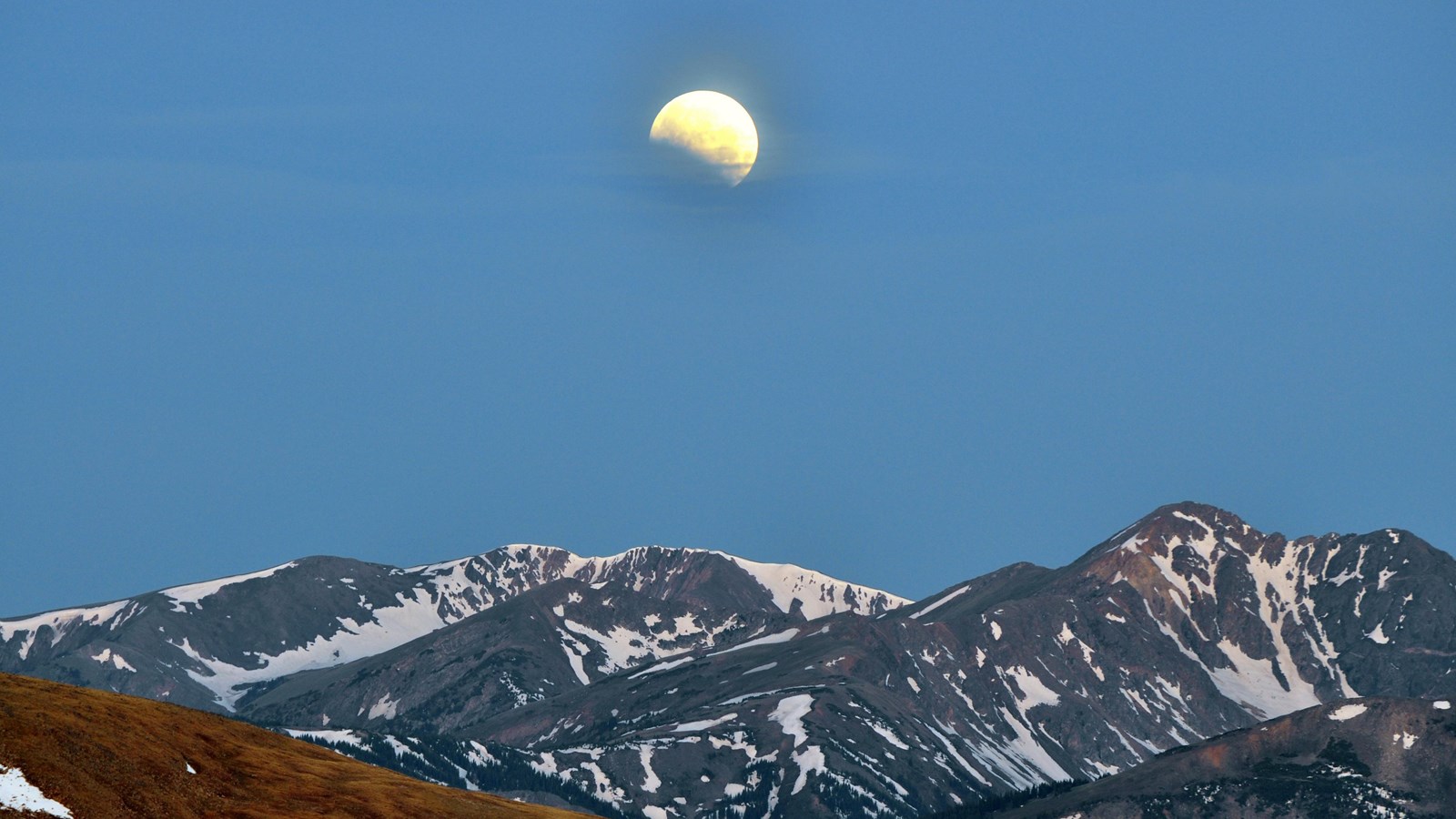 Moon seen rising over mountain peaks