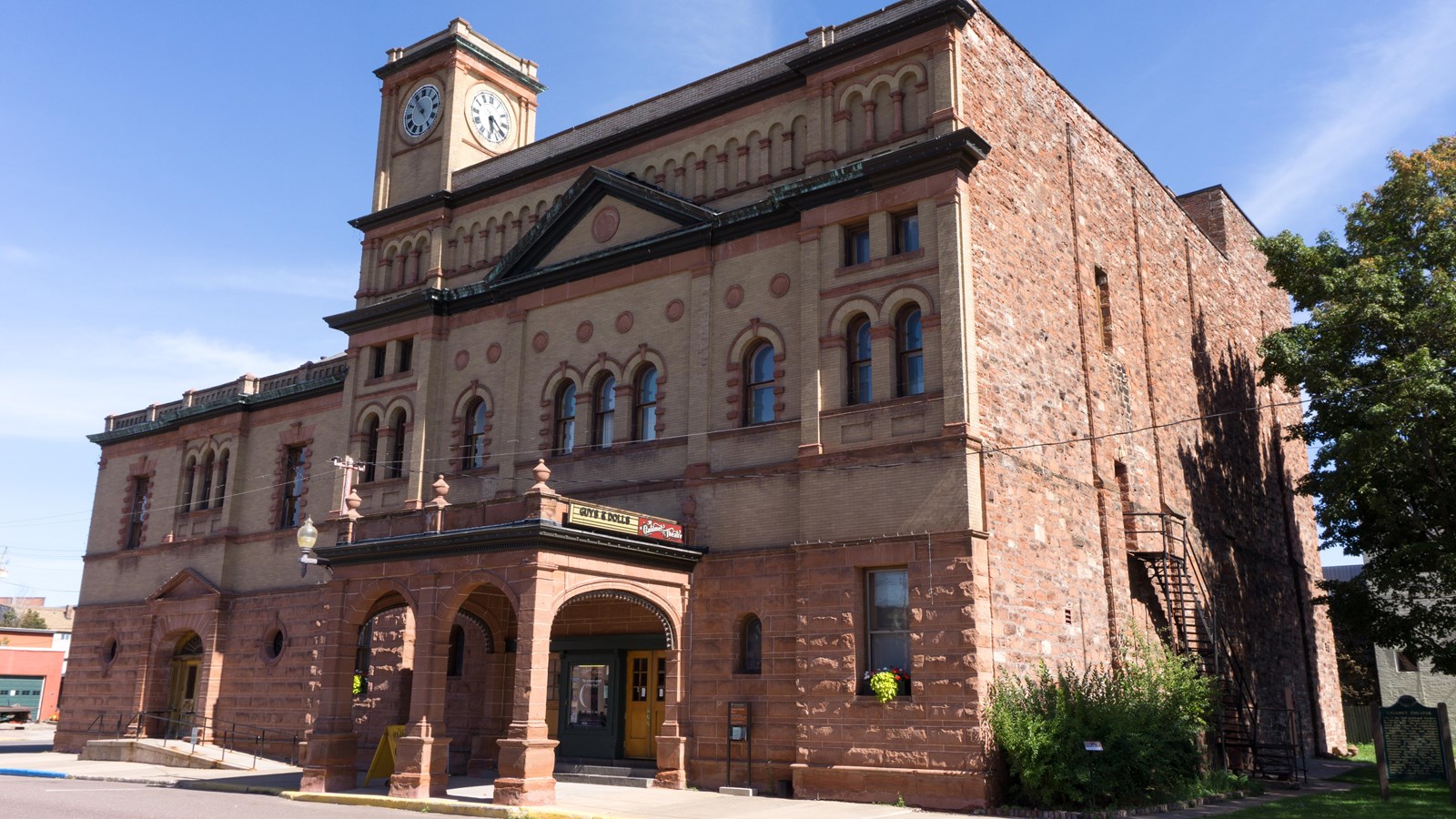 Summer scene of a red Jacobsville sandstone building with yellow brick front.