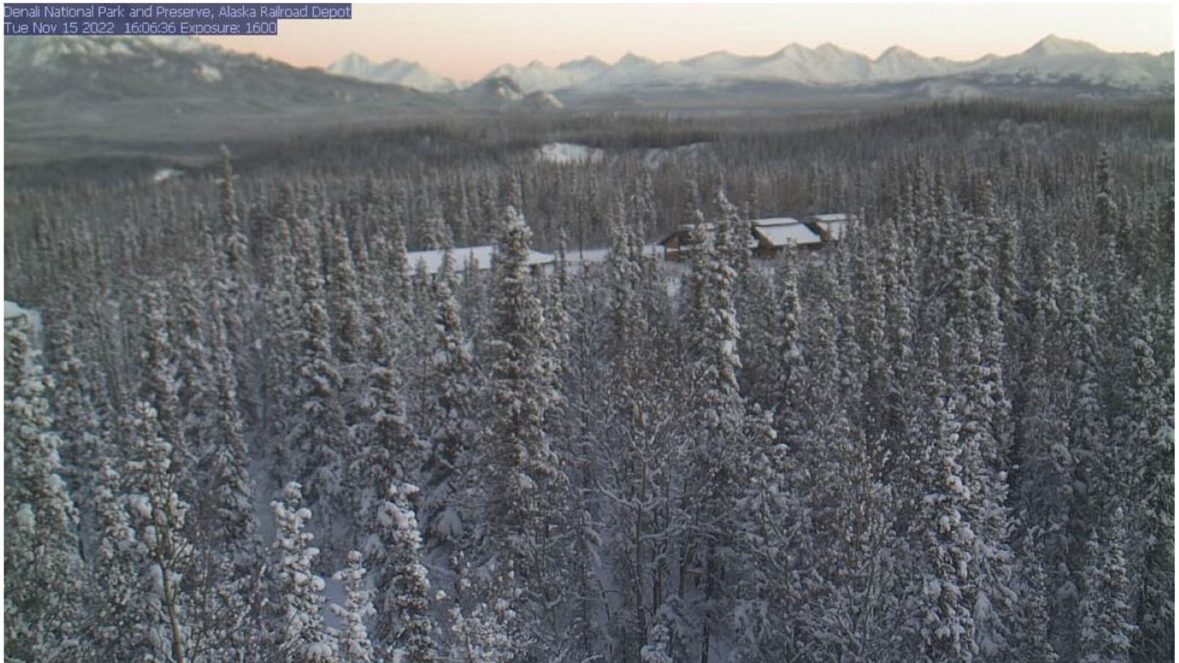 View of railroad depot, forest, distant mountains