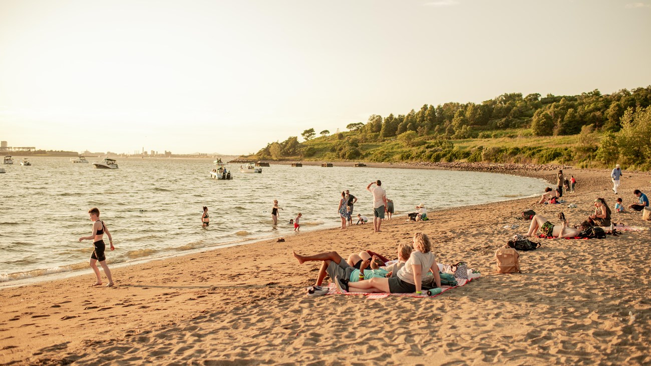 view of the Spectacle beach at sunset with people on the beach and swimming in the water.