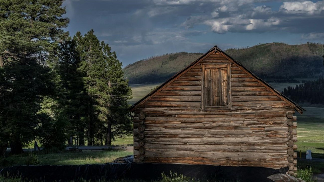 The back of a historic wooden building overlooking a montane grassland
