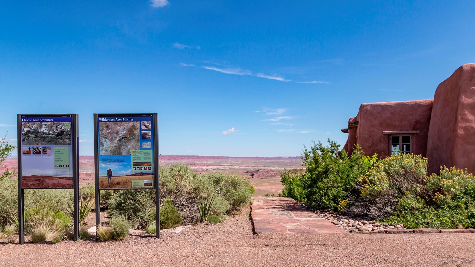 Two signs at the trailhead next to the Pueblo Revival Style inn