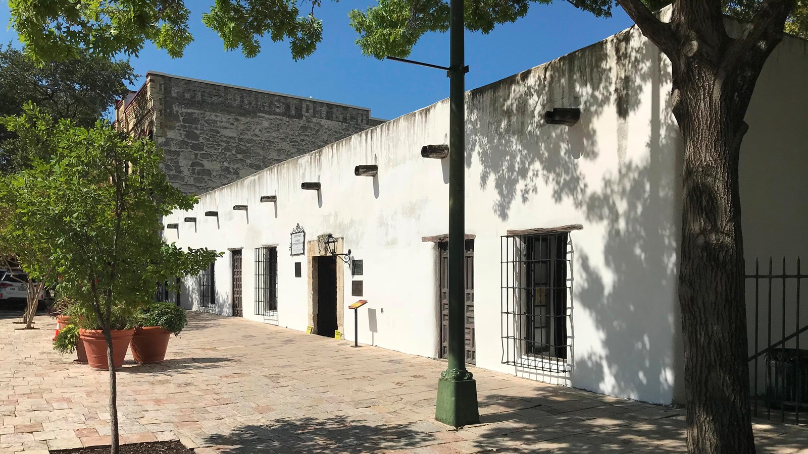 A long, single story stucco building with a tile plaza.