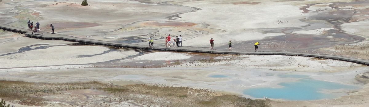 Visitors walk along a boardwalk that meanders by several hot springs.