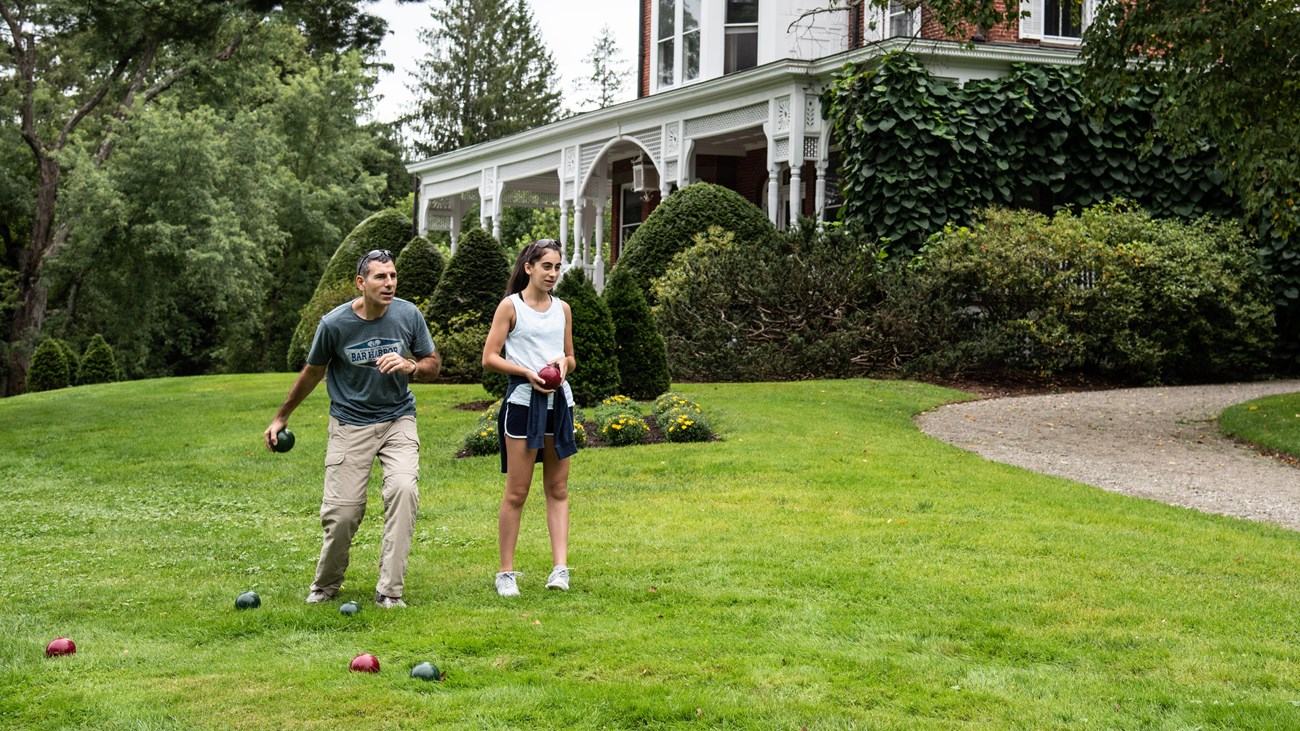 Two park visitors play bocce ball in front of the Marsh-Billings-Rockefeller mansion