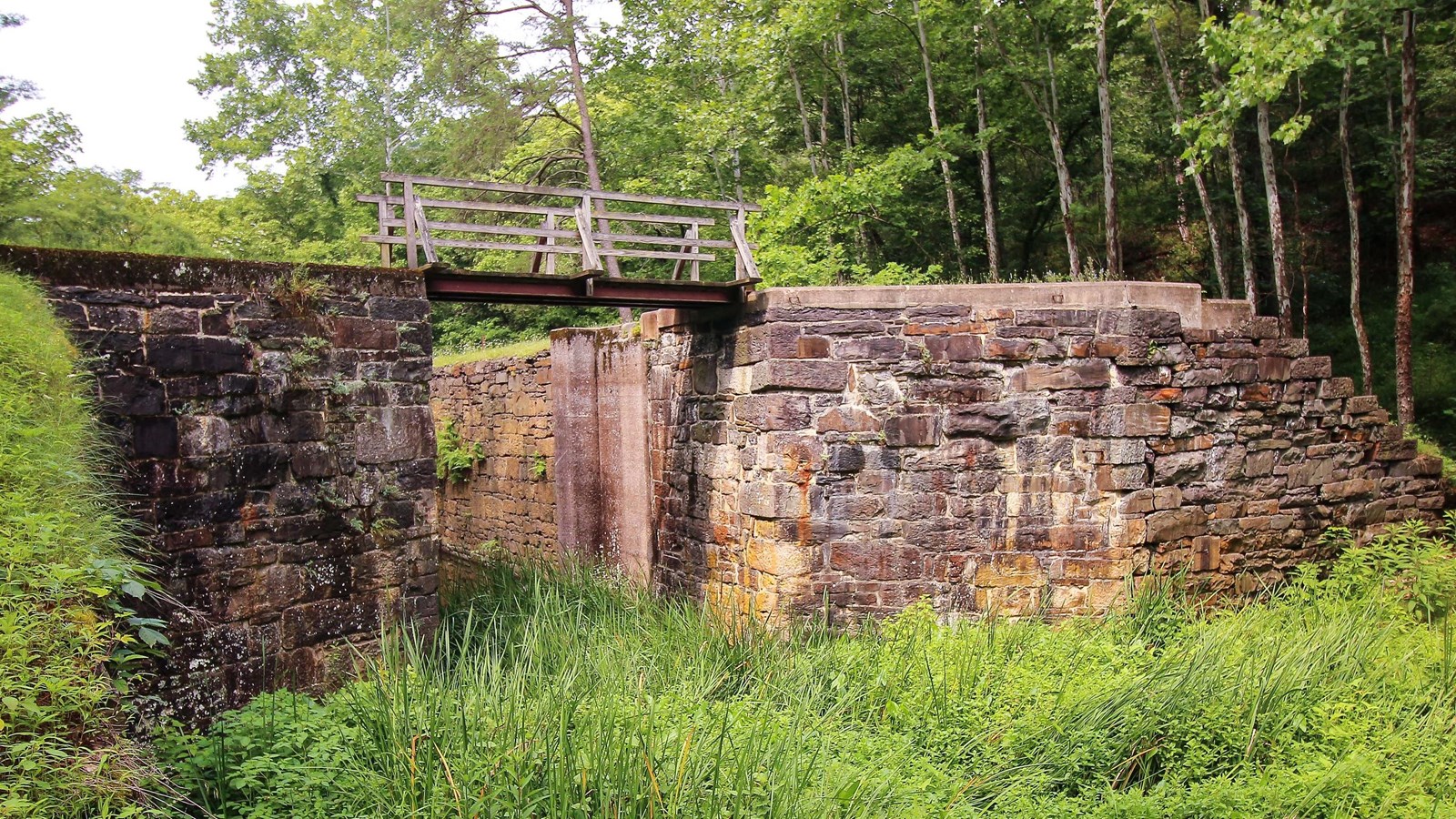 A water filled lock with a foot bridge spanning the rock lock walls.