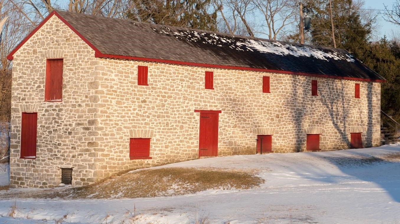 A modern day image of the stone long house with snow on the ground.